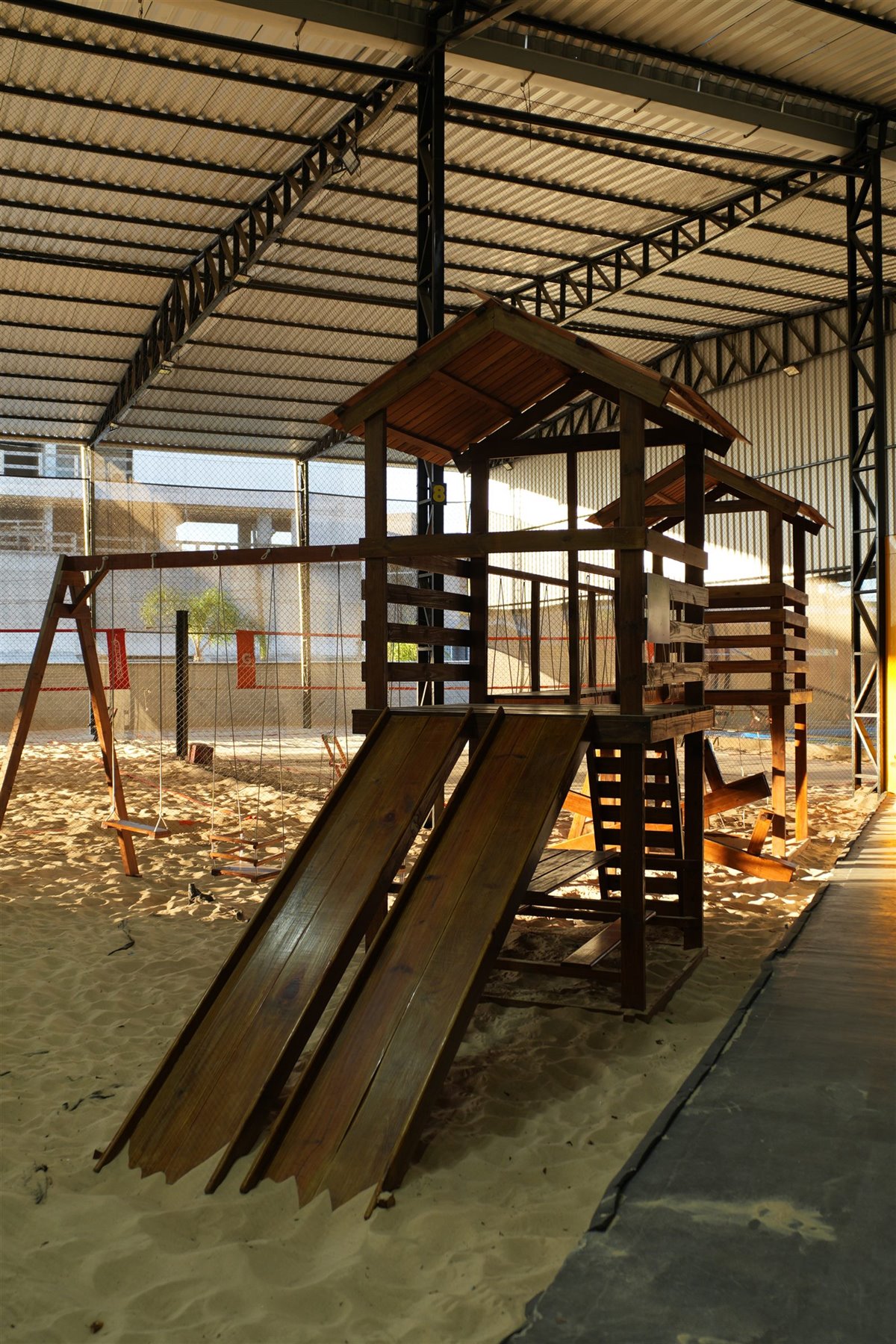 Espaço Kids com playground de madeira na areia